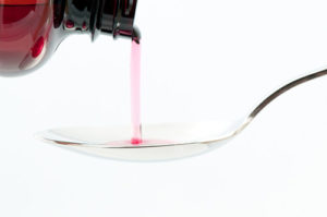 codeine cough syrup being poured into a spoon - codeine side effects