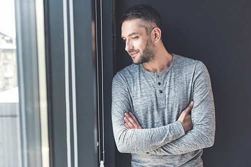 man looks out window at recovery facility